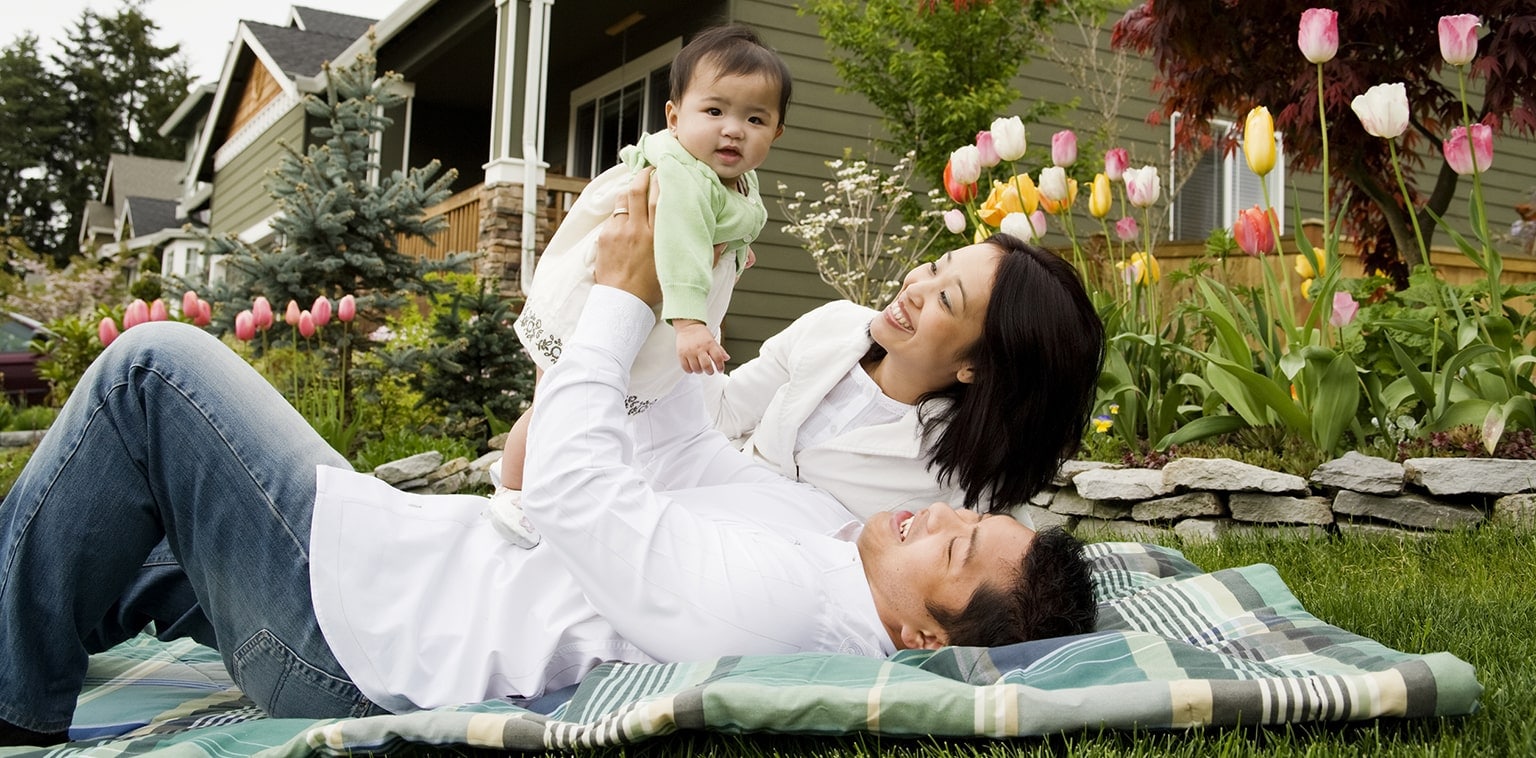 Young family relaxing in yard with tulips and home in the background