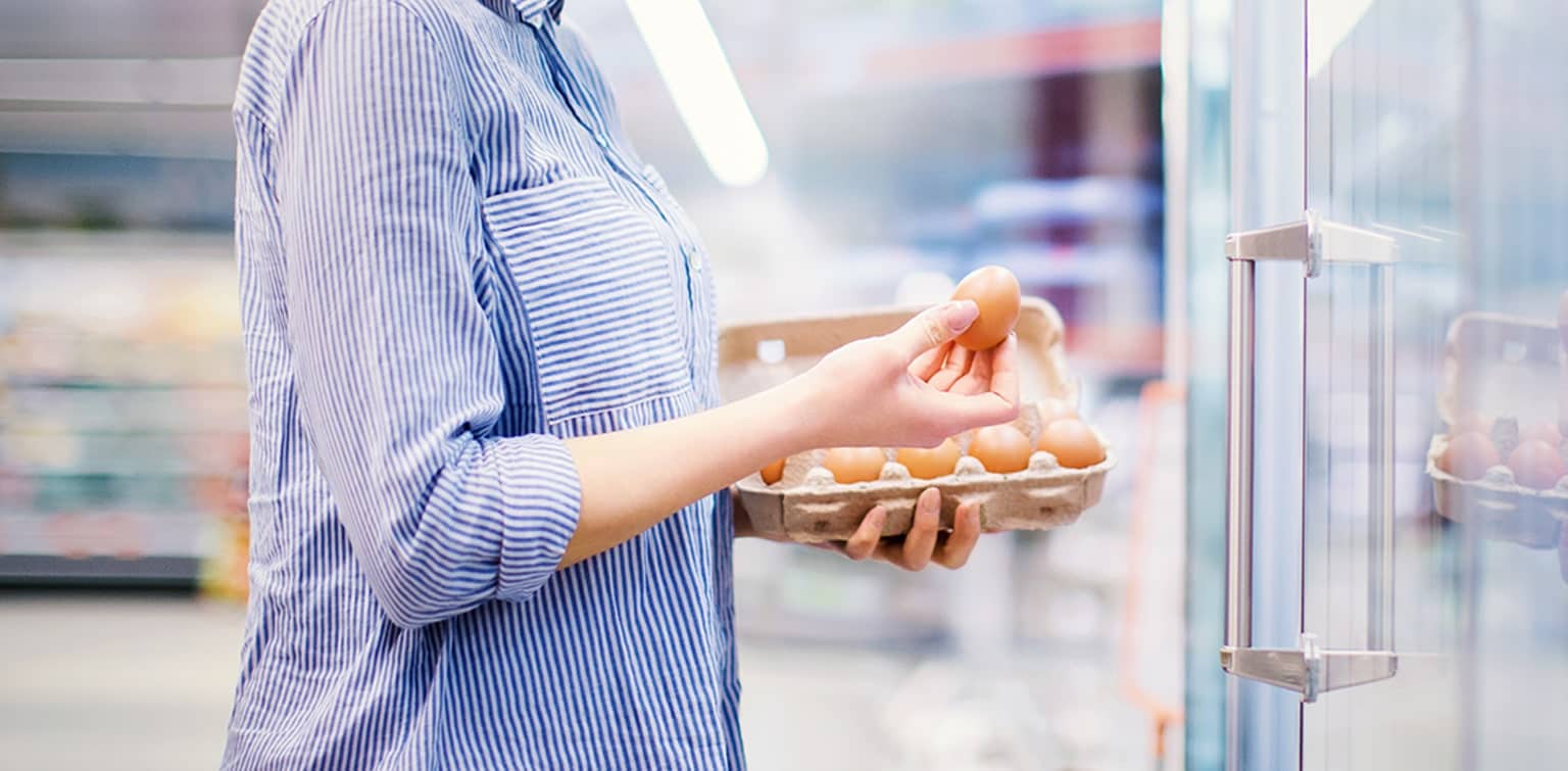 Woman purchasing eggs at a grocery store