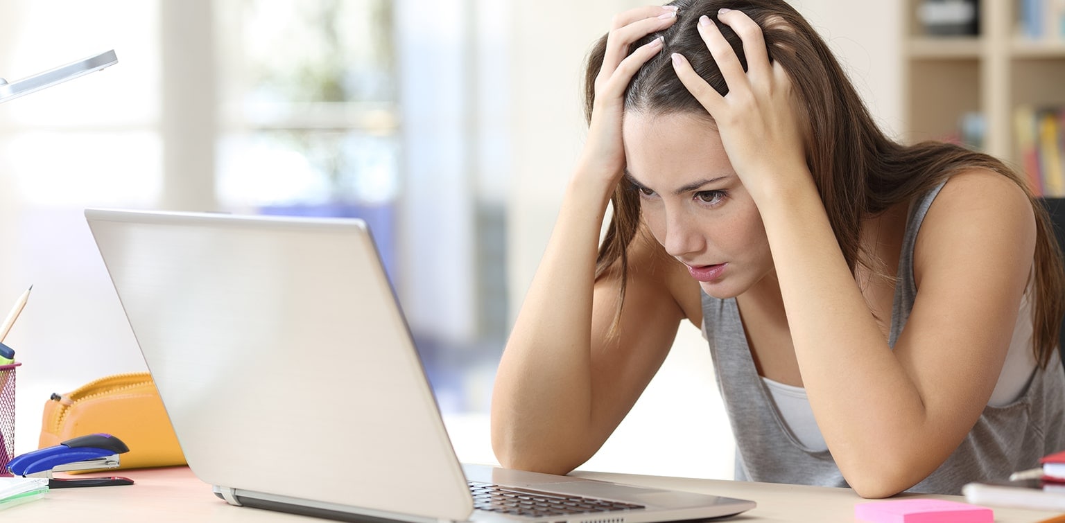 Frustrated female college student looking at laptop monitor