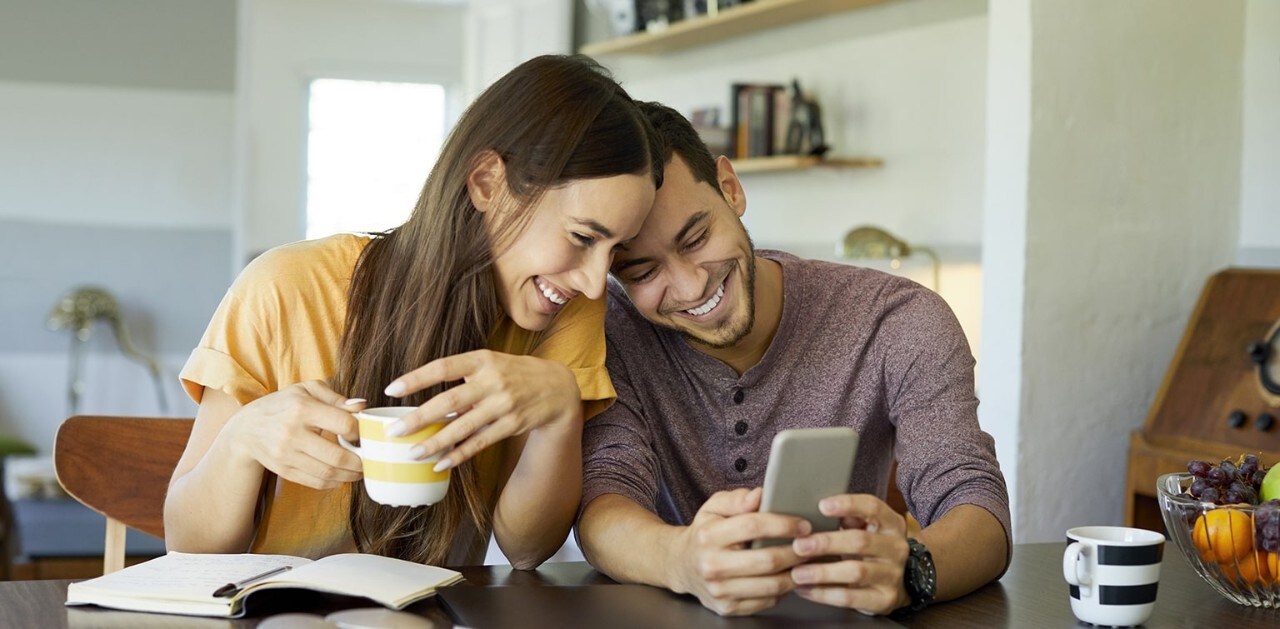 Couple sitting at table looking at smartphone