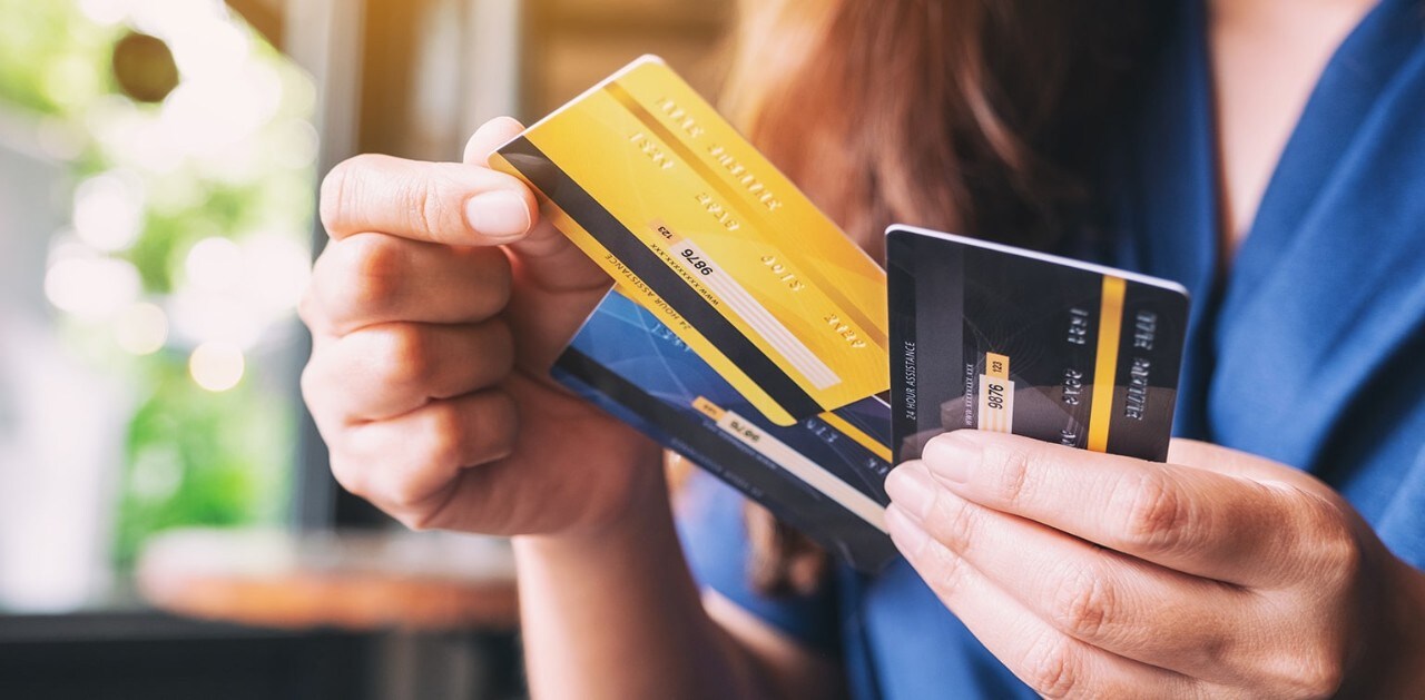 Woman holding three credit cards and selecting one from the middle