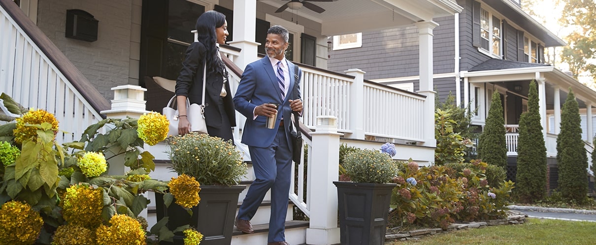 African-American couple walking down front steps of home in residential neighborhood