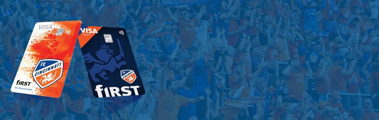 First Financial Bank FC Cincinnati credit and debit cards over orange and blue diagonal lines on a dark blue background