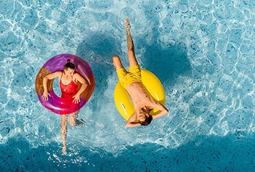 Overhead view of young Caucasian couple relaxing in rafts in swimming pool