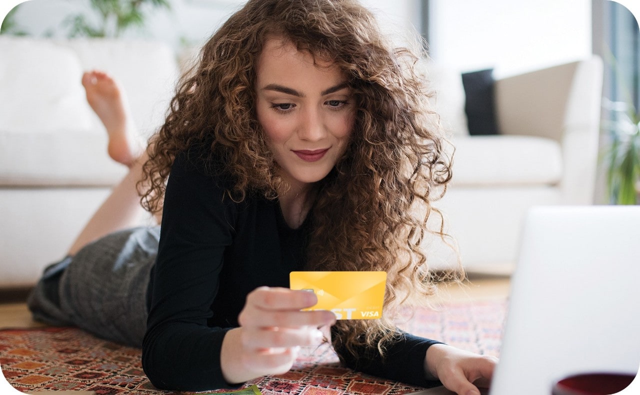 Young Caucasian woman on laptop using First Financial debit card