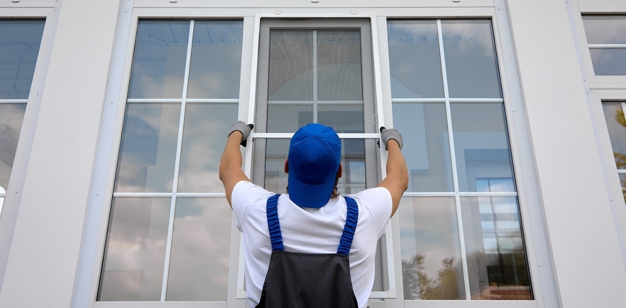 A man in coveralls hanging a new window