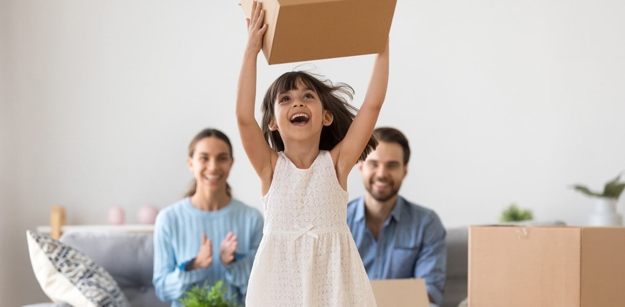 Small child holding a box behind adoring parents