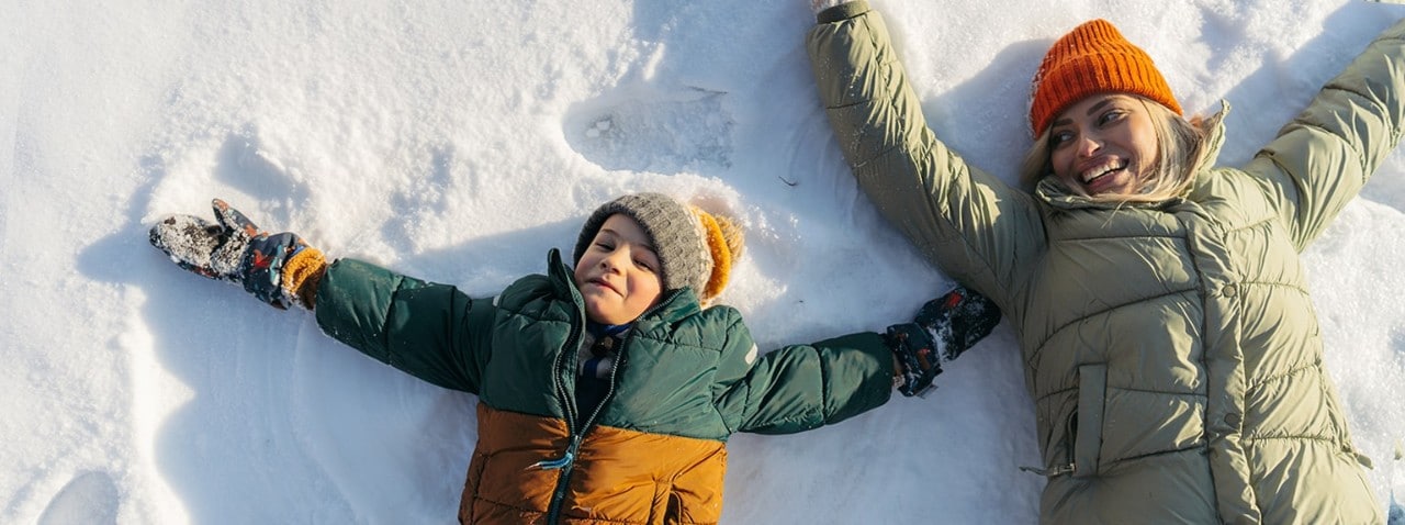 Parent next to child making snow angels