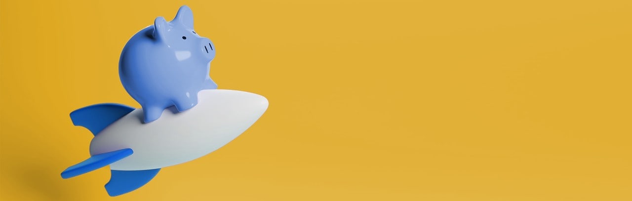 A blue piggy bank sits atop a white rocket, symbolizing savings and aspirations for adventure