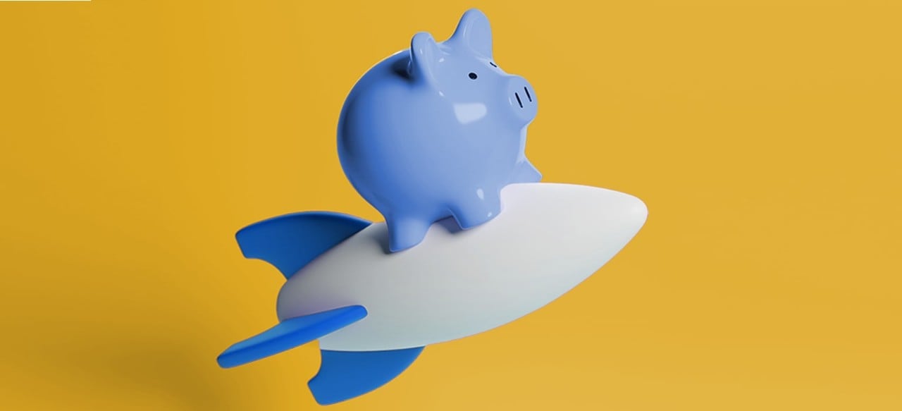 A blue piggy bank sits atop a white rocket, symbolizing savings and aspirations for adventure.
