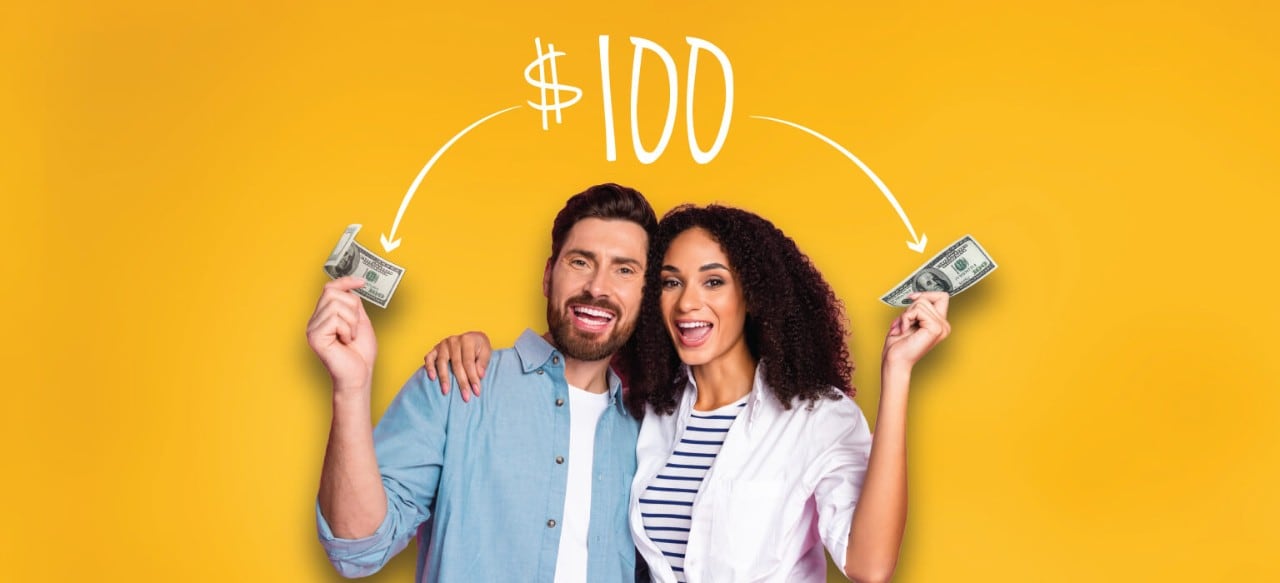 Smiling young couple each holding $100 bills