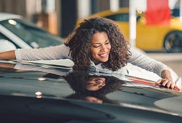 Woman admiring a luxury car in a dealership