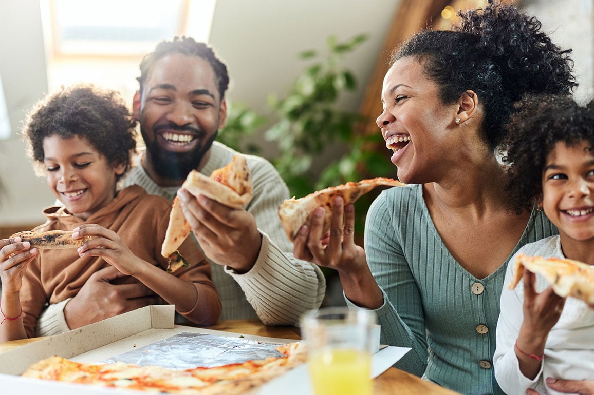 Smiling African-American family eating pizza