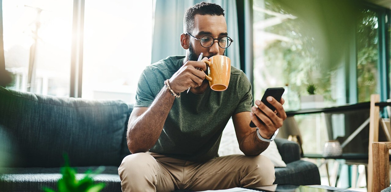 African-American man sipping coffee and looking at smartphone