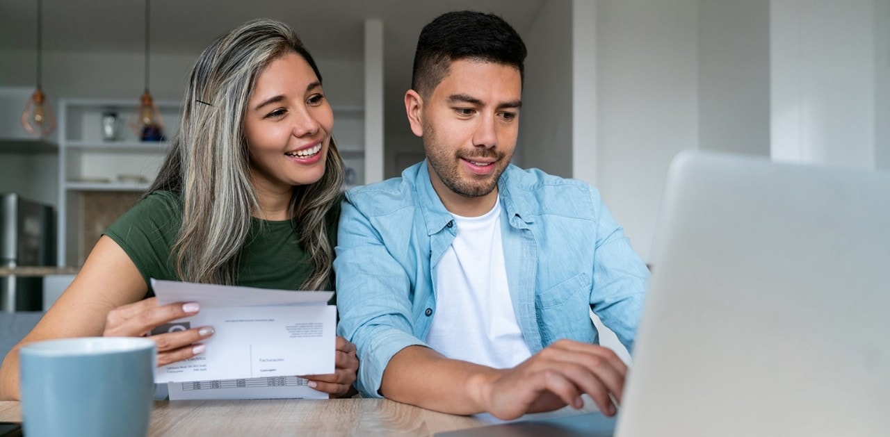 Happy couple paying bills on laptop computer