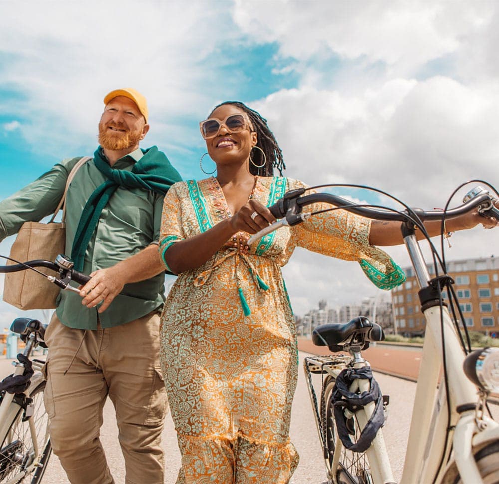 Middle-aged multi-racial couple walking with bicycles