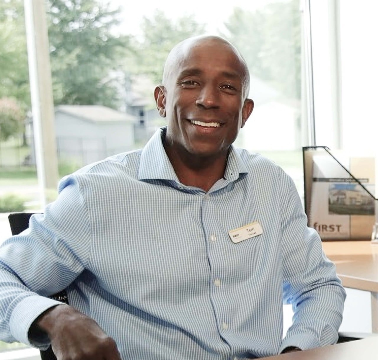Smiling male African-American banker sitting at desk in a First Financial office