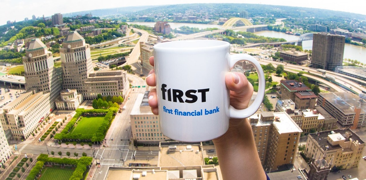 Woman’s hand holding First Financial mug in front of downtown Cincinnati background