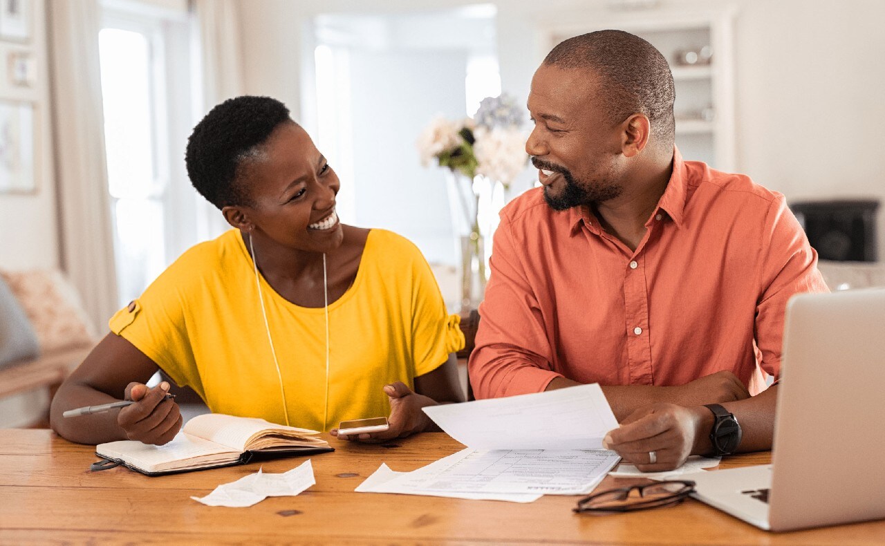 Smiling African-American couple reviewing financial paperwork