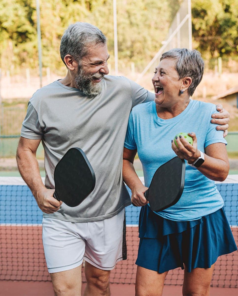 Smiling senior couple playing pickleball