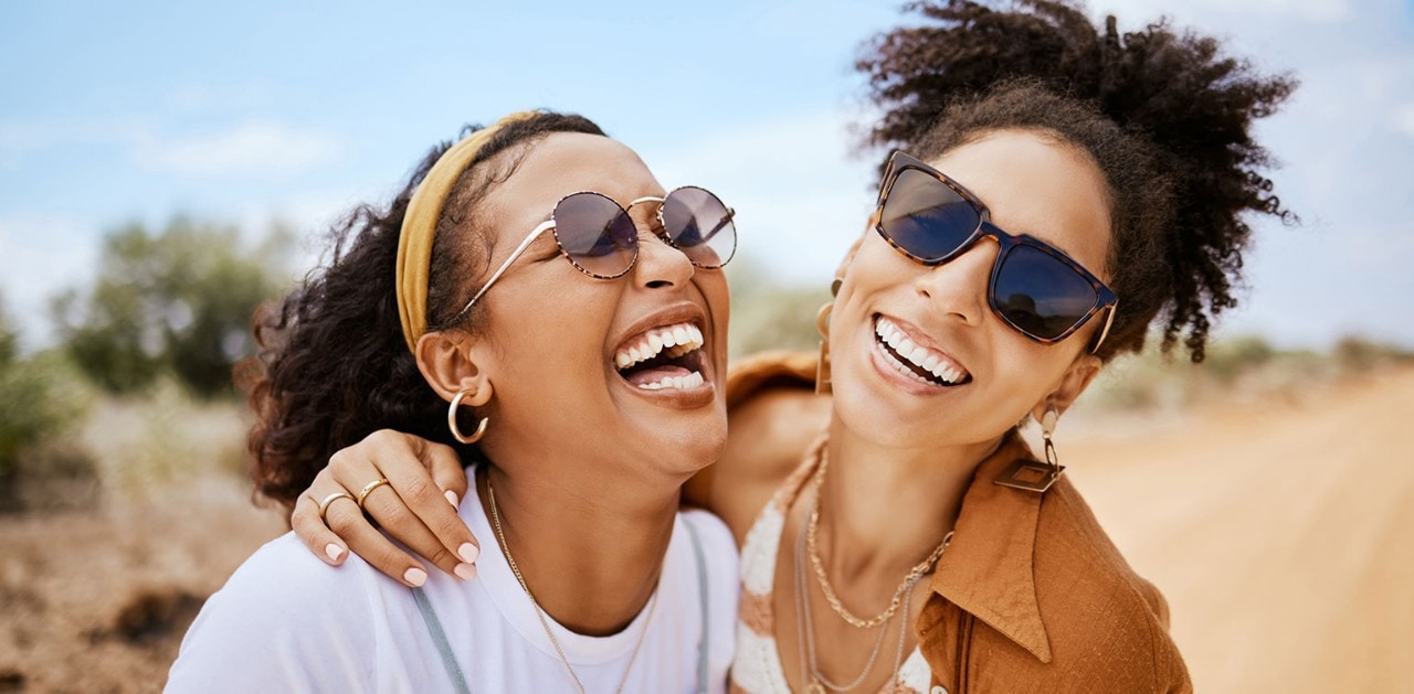 Two young African-American women smiling and hugging