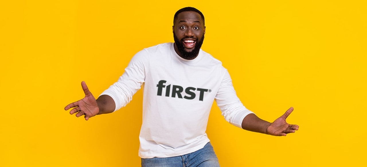 Happy man with outstretched arms wearing a First Financial Bank t-shirt against a yellow background