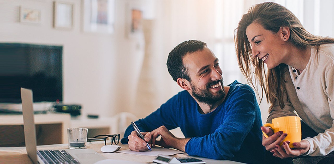 Couple at desk with laptop reviewing financial documents