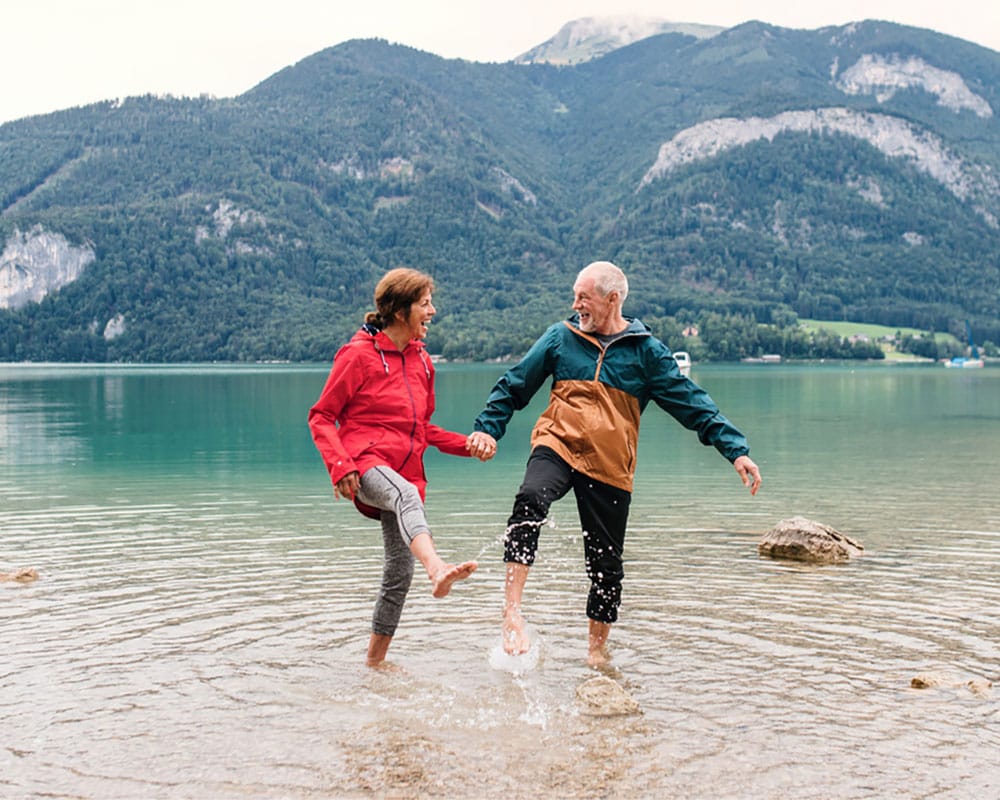 Middle-aged couple wading and splashing in a mountain lake