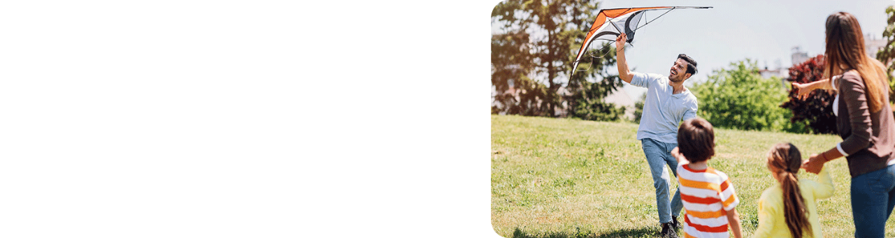 Mother and two young children watching as father flies a kite