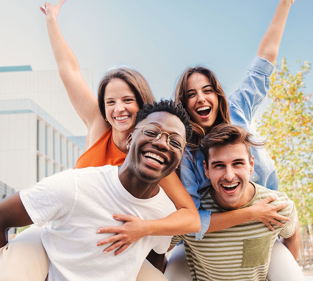 Two young men giving piggyback rides to two young women