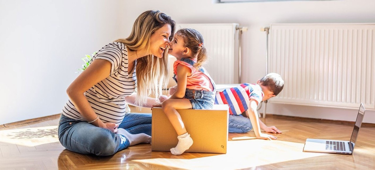 Pregnant mother playing with son and daughter on floor of home