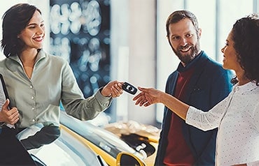 Car saleswoman handing keys to multiracial couple