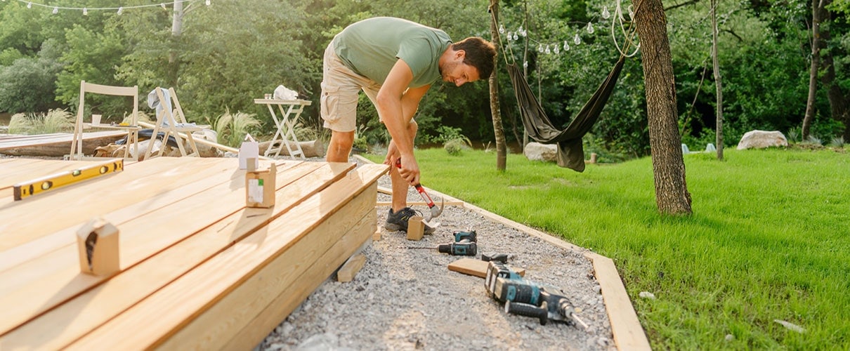 Carpenter building a deck in a back yard
