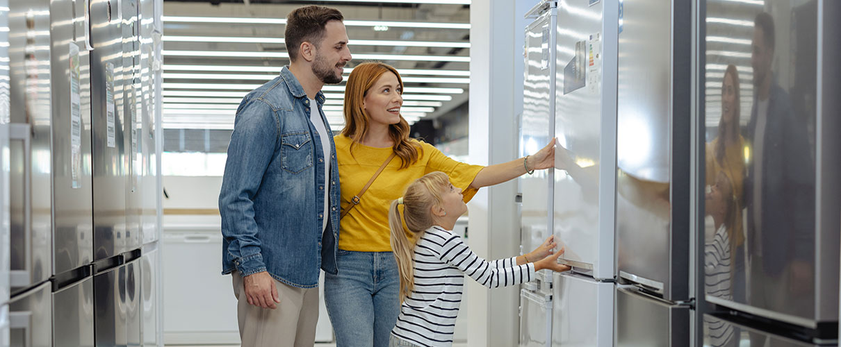 Couple and young daughter refrigerator shopping in an appliance store