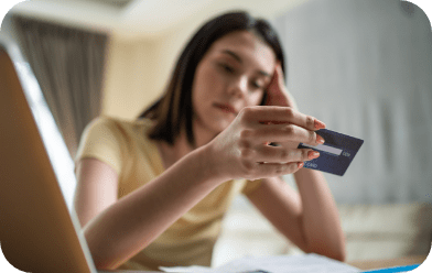 Woman with concerned facial expression holding credit card