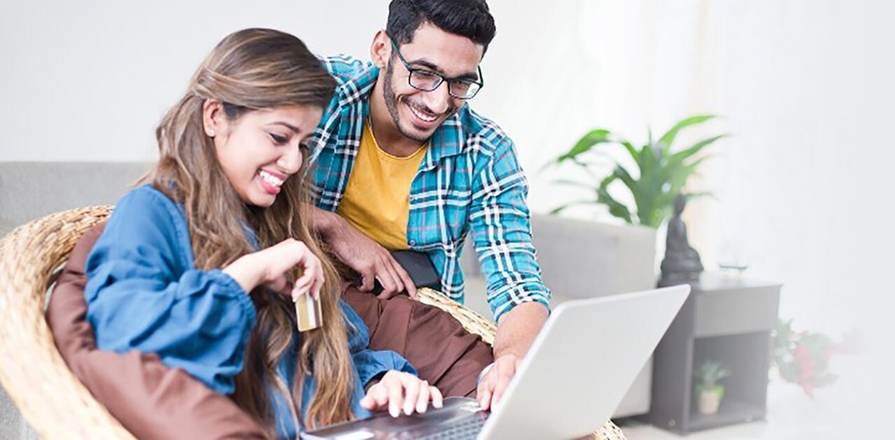 Couple sitting on couch looking at laptop