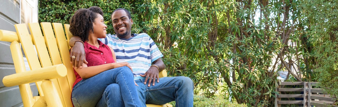 African-American couple sitting on Adirondack bench in yard