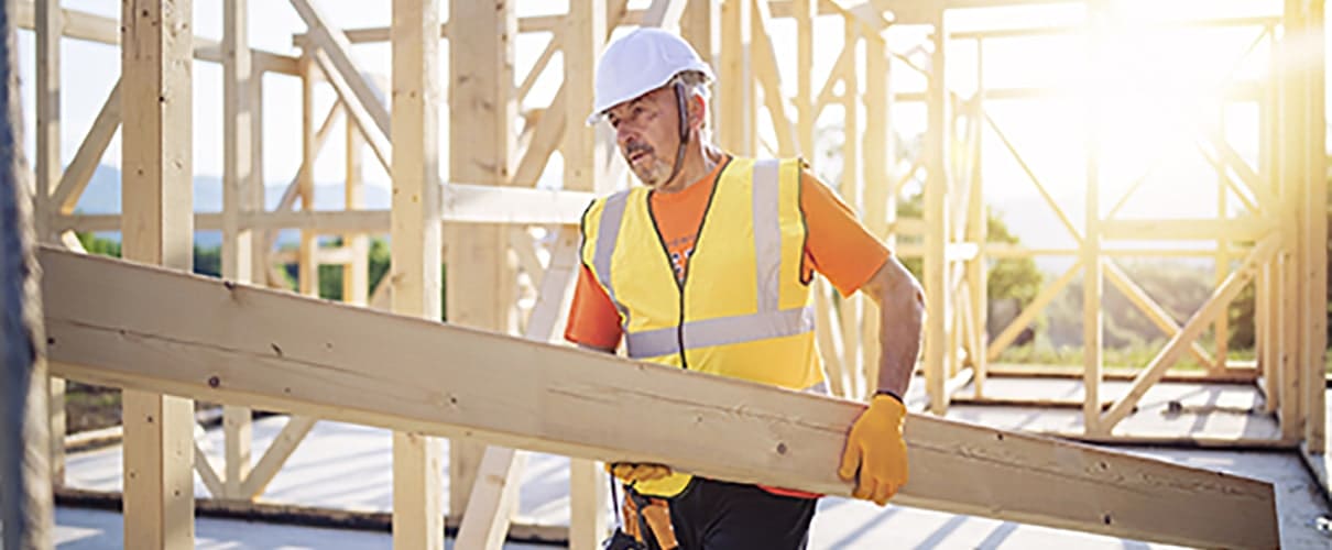 Construction worker carrying lumber at a home building site