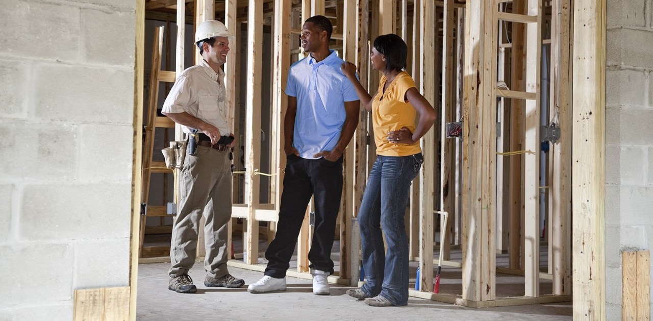 African-American couple talking to contractor in partially built home