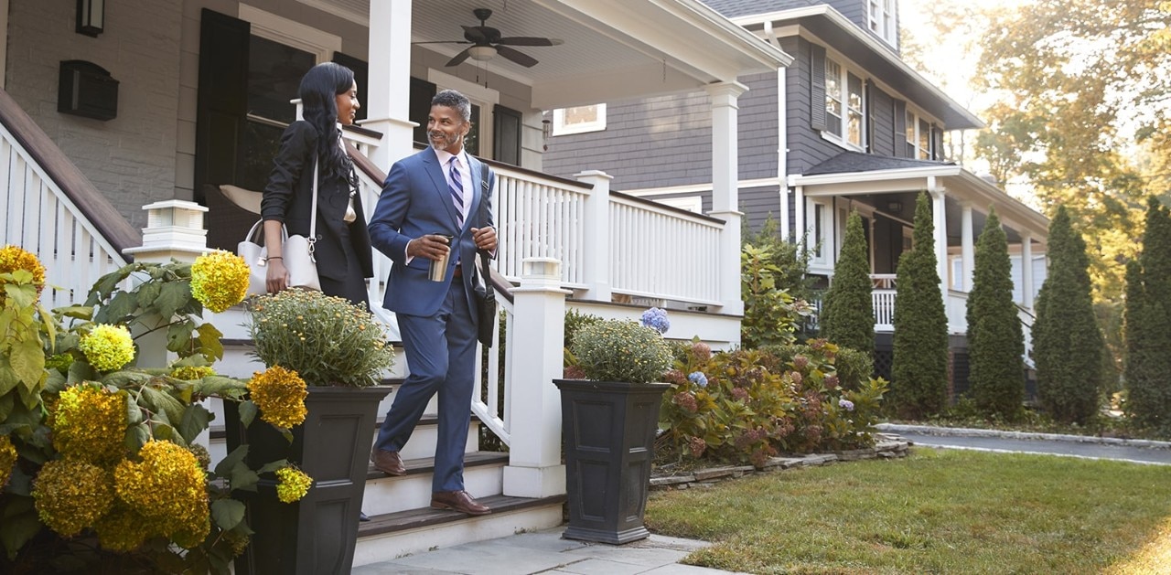 African-American couple walking down front steps of home in residential neighborhood
