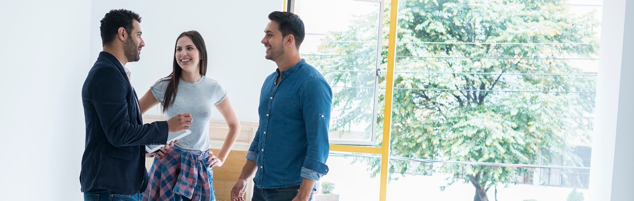 Real estate agent answering questions of young couple in house