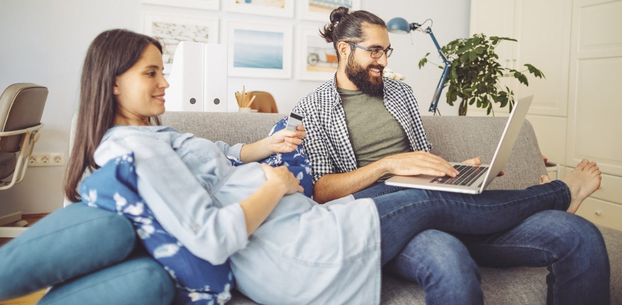 Man using laptop on couch with pregnant wife