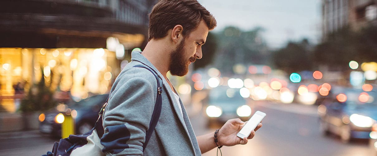 Young man using smartphone in busy city setting