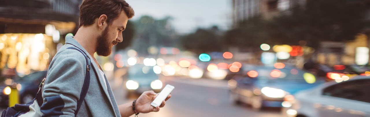 Young man using smartphone in busy city setting