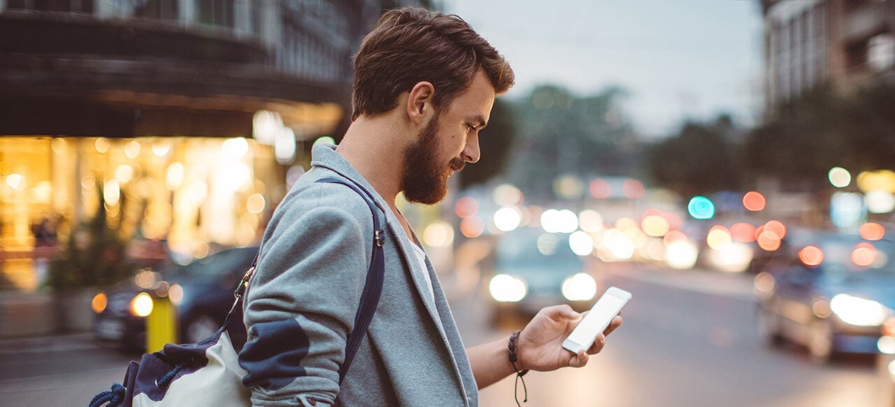 Young man using smartphone in busy city setting