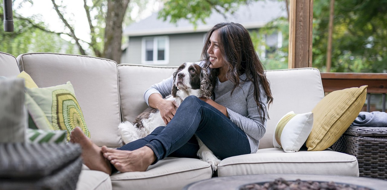 Women snuggling with dog on outdoor patio sofa