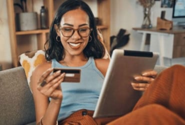 Smiling African-American woman making credit card purchase using tablet