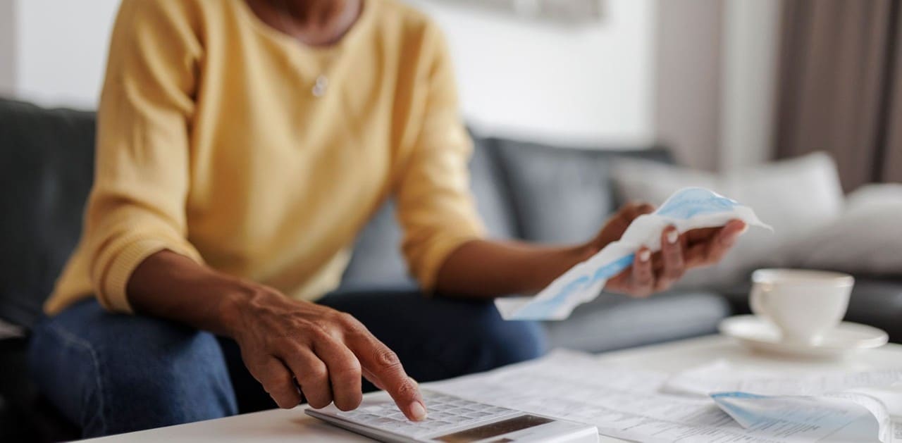 Close-up of African-American woman's hands as she uses a calculator and pays bills