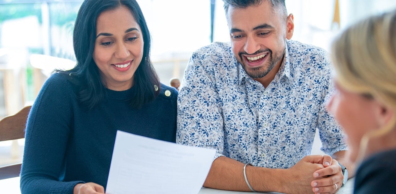 Smiling couple reviewing loan documents with banker