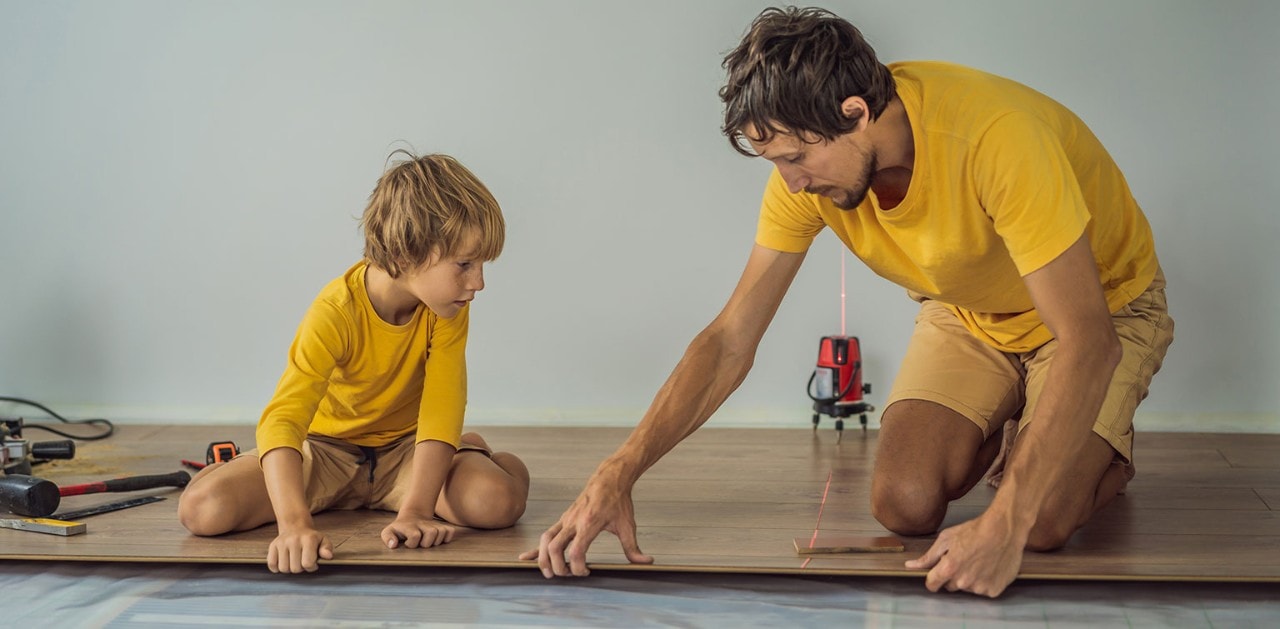 Father and young son installing flooring